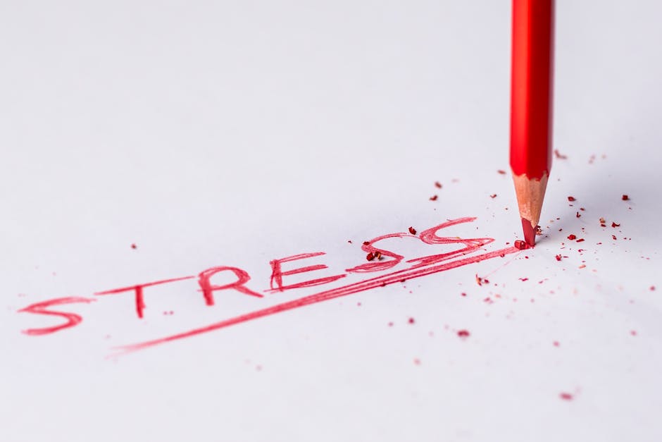 Close-up of a red pencil writing 'stress' on paper, symbolizing pressure and creativity.