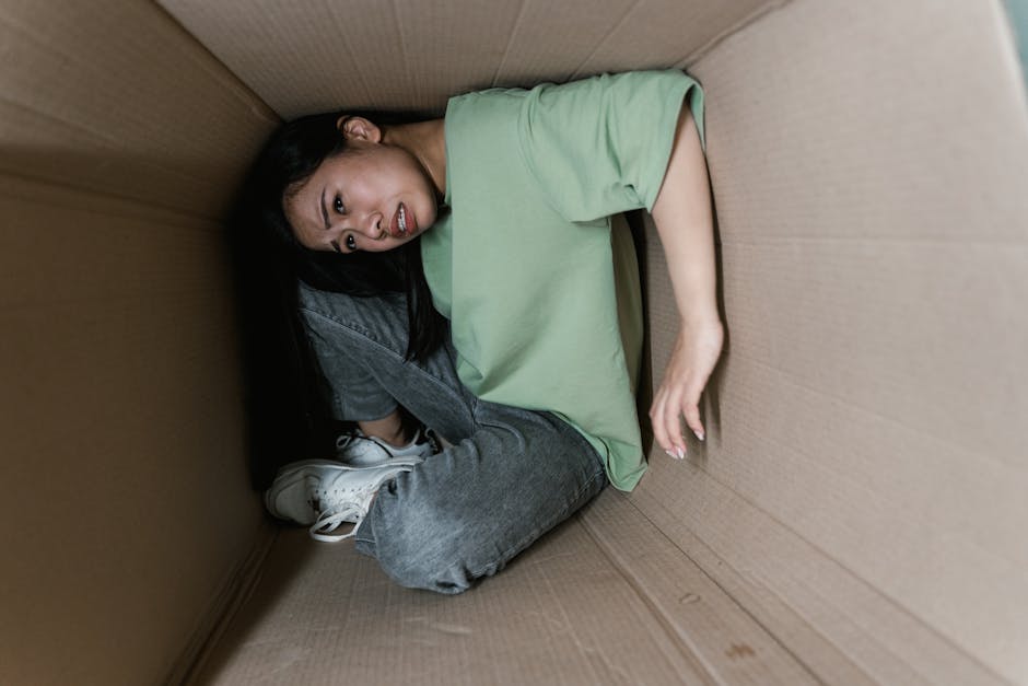 A woman trapped inside a cardboard box, symbolizing anxiety and fear.